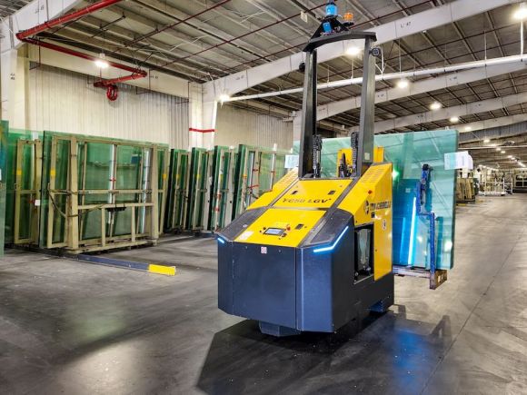 Immagine di un Forklift AGV a guida autonoma in attività in un contesto di vetro industriale.